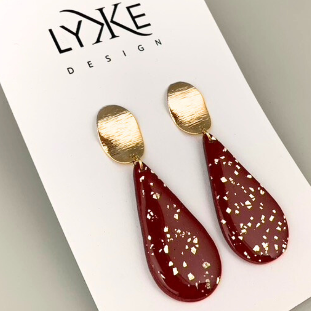 Gullfargede øredobber med stor rød dråpe med gullblad-effekt