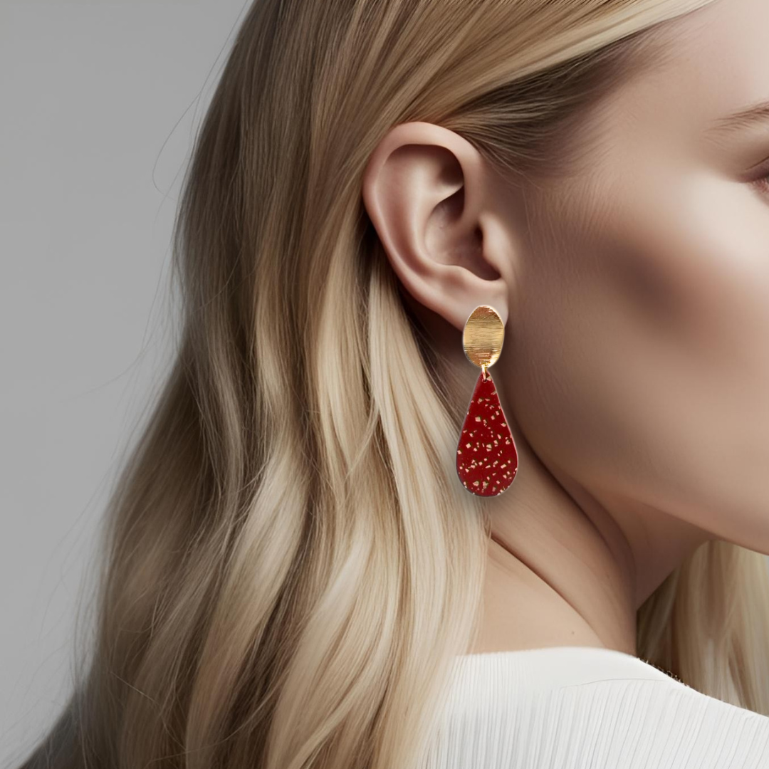 Gullfargede øredobber med stor rød dråpe med gullblad-effekt