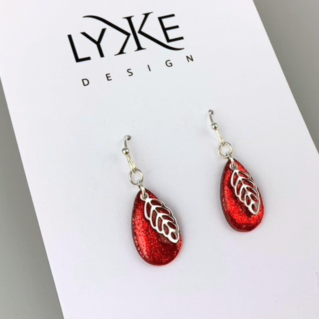 Sølvfargede øredobber med glitrende rød dråpe og sølvblad