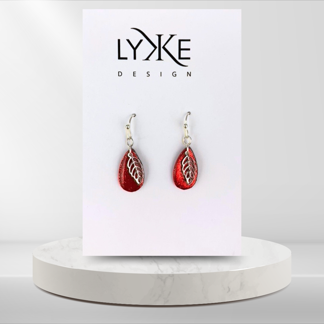 Sølvfargede øredobber med glitrende rød dråpe og sølvblad