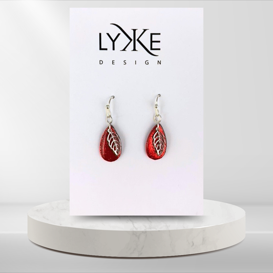 Sølvfargede øredobber med glitrende rød dråpe og sølvblad